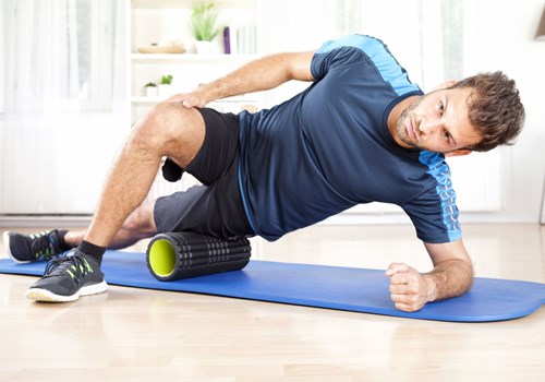 A male exercising with a foam tube on a yoga mat