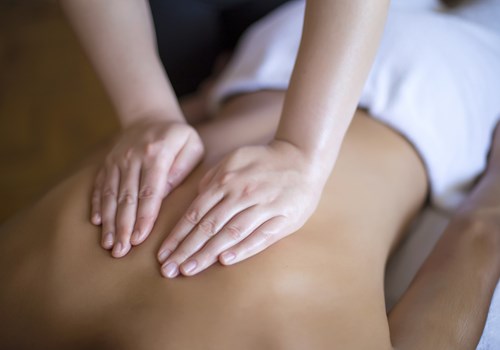 A female chiropractor pushing on a male patients back from above, cupping her hands