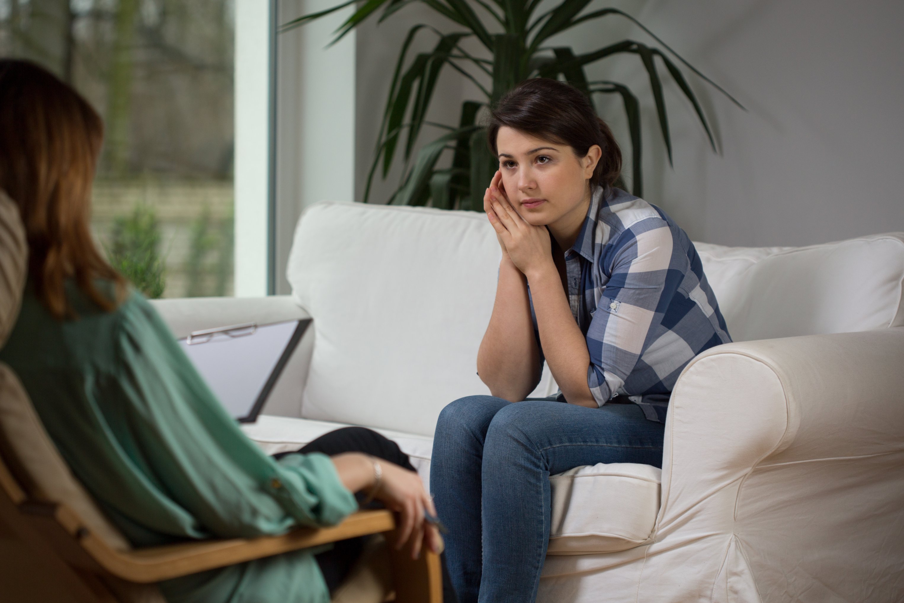 A female psychologist talking to a female patient, both sitting in on comfortable couches