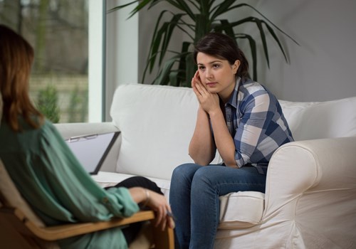 A female psychologist talking to a female patient, both sitting in on comfortable couches