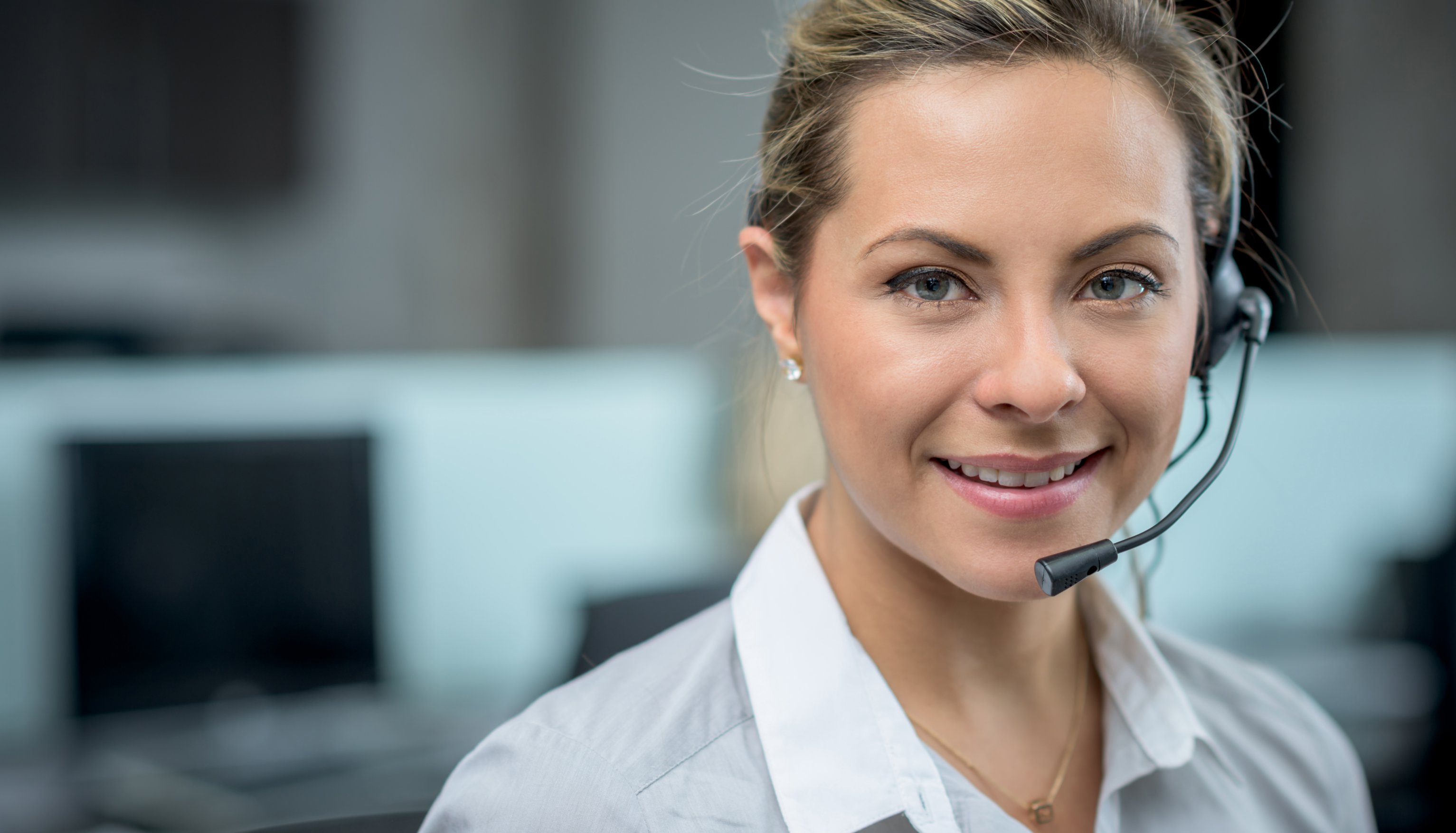 A female receptionist wearing a headset smiling at the camera