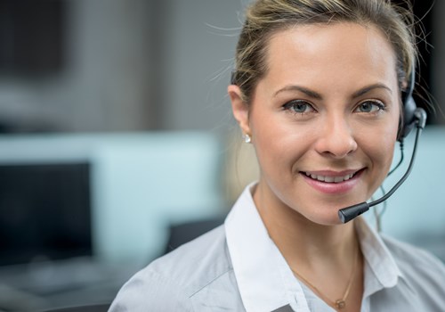A female receptionist wearing a headset smiling at the camera