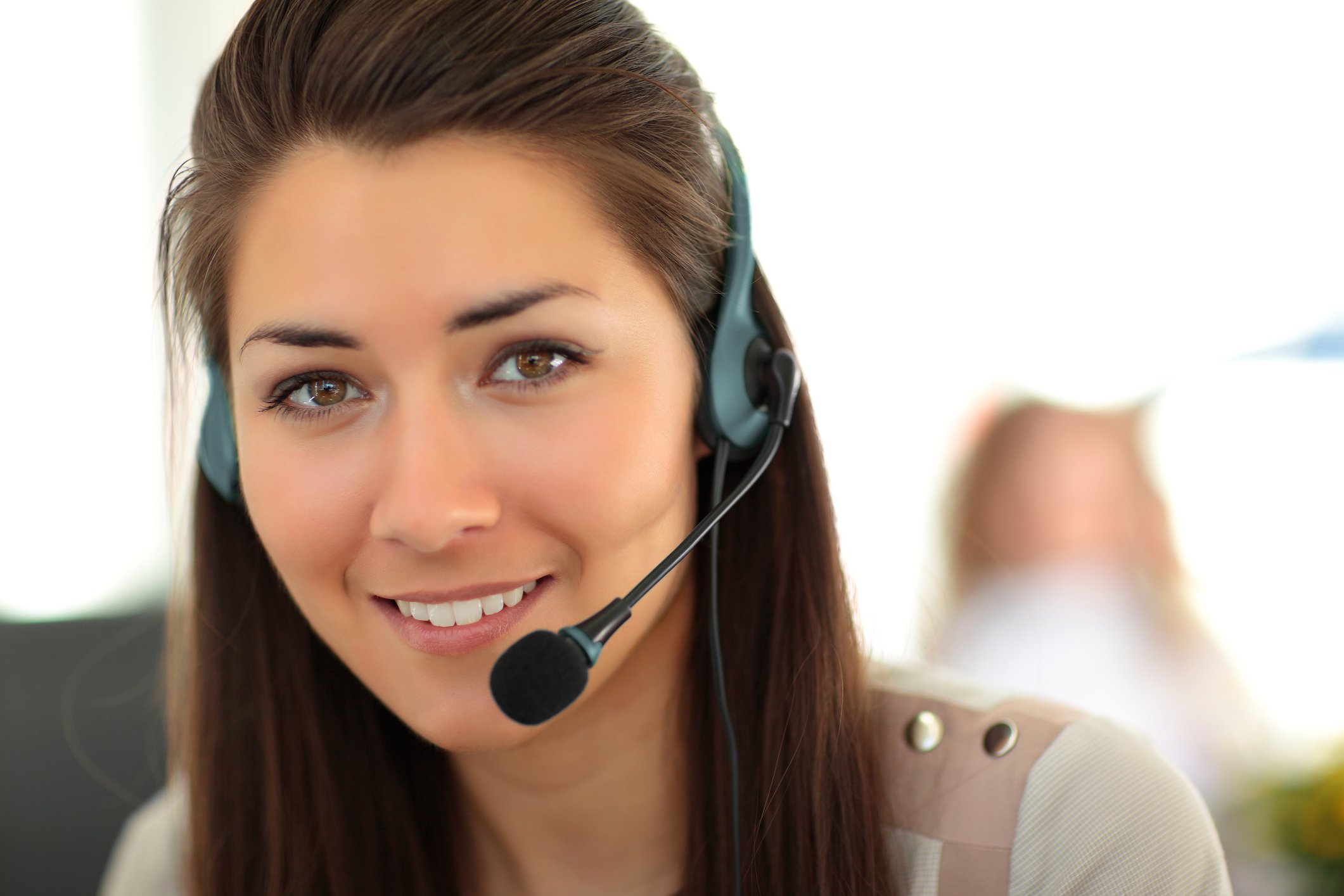 A female receptionist wearing a headset smiling at the camera