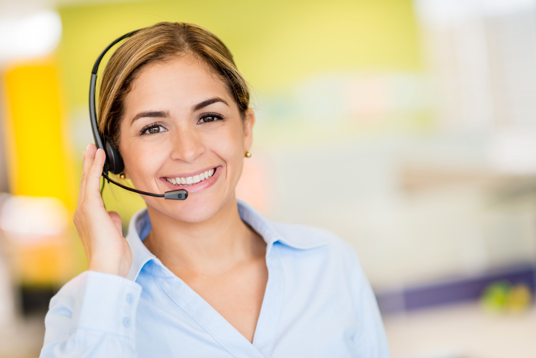 A female receptionist wearing a headset smiling at the camera
