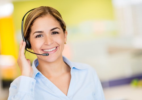A female receptionist wearing a headset smiling at the camera