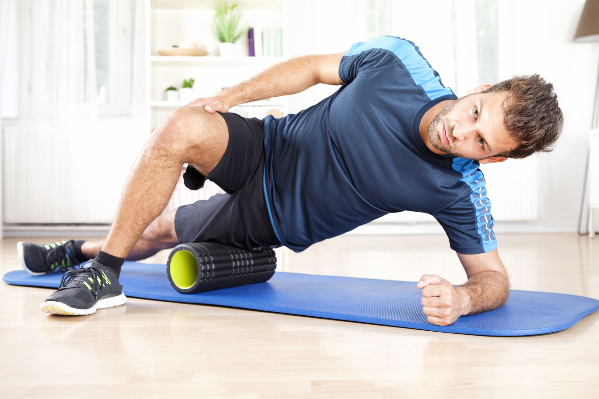 A male exercising with a foam tube on a yoga mat