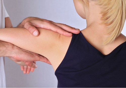 A male osteopath stretching a female patients shoulder