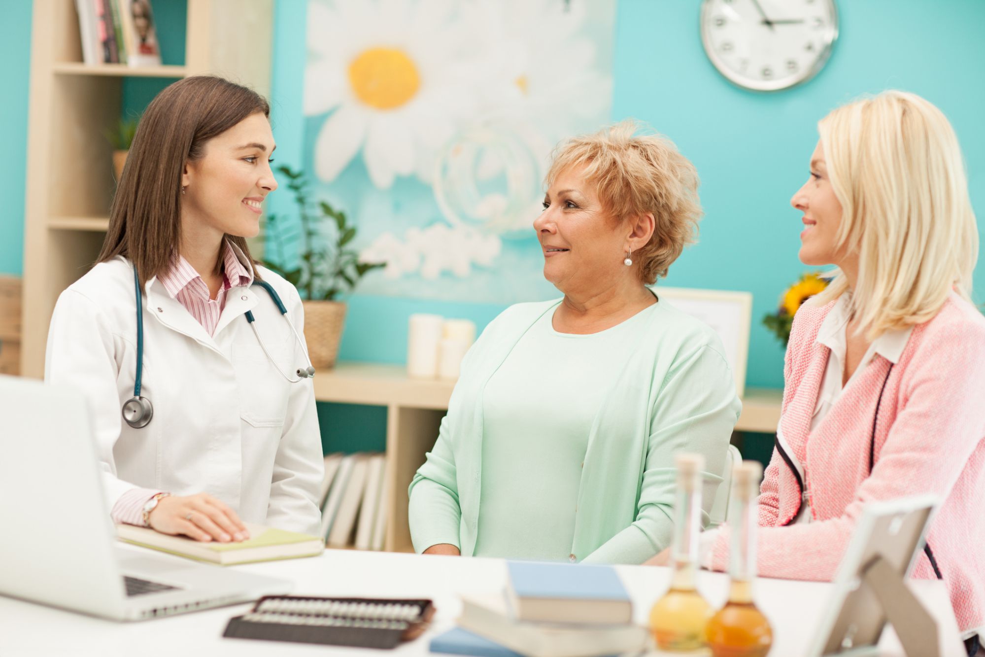 A female doctor talking to an older woman and a younger woman in a floral decorated office