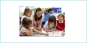 A female teacher drawing with a group of children in a classroom