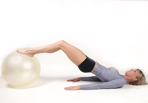 A woman using an exercise ball to stretch