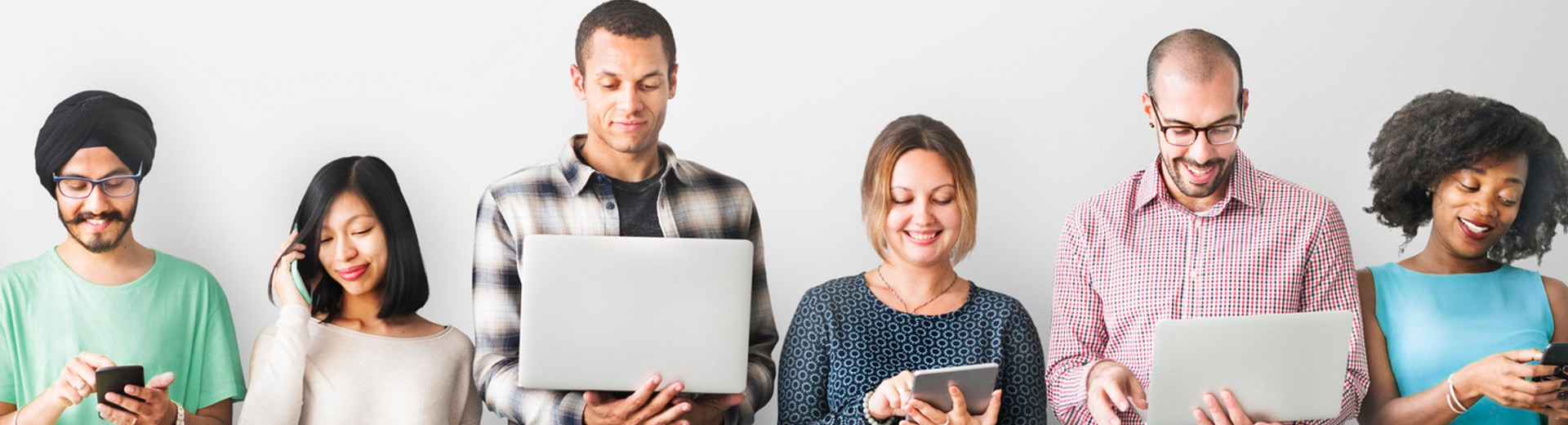 Six people resting against a wall using laptops, phones and tablets