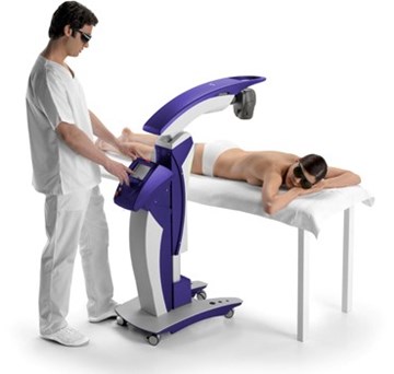 A male laser technician currently treating a female patient laying on her chest with a large laser therapy machine
